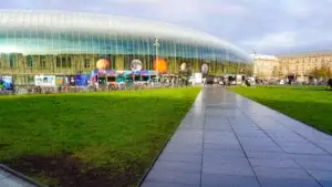 Façade contemporaine en verre de la gare de Strasbourg avec pelouse verte et vélos stationnés à l'avant.